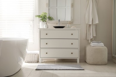 Photo of Stylish mat with pattern near chest of drawers in bathroom