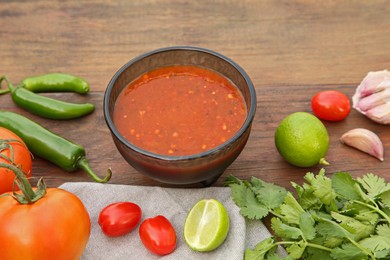 Photo of Tasty salsa sauce and different ingredients on wooden table