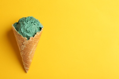 Photo of Delicious spirulina ice cream cone on color background, top view. Space for text