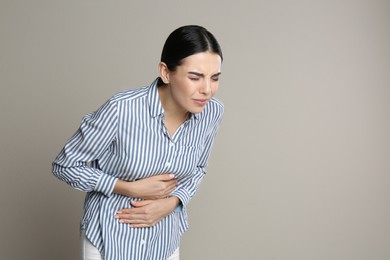 Photo of Woman suffering from stomach ache on beige background, space for text. Food poisoning