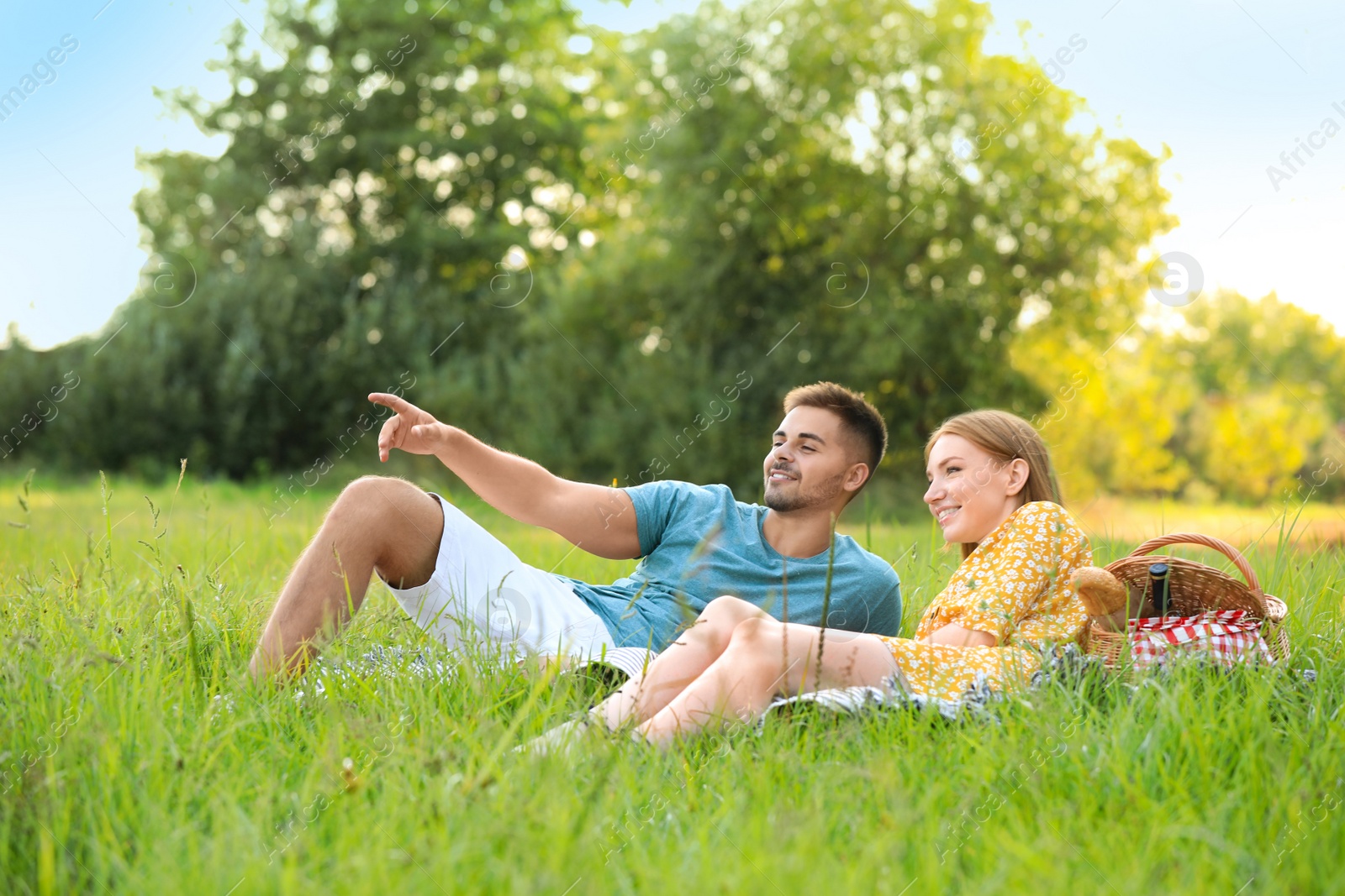 Photo of Happy young couple having picnic on green grass in park