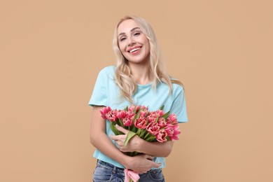 Happy young woman with beautiful bouquet on beige background