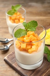 Photo of Delicious panna cotta with mango on wooden table