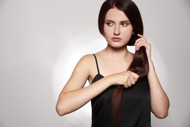 Photo of Beautiful young woman with healthy strong hair posing in studio, space for text