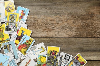 Photo of Tarot cards on wooden table, top view. Space for text