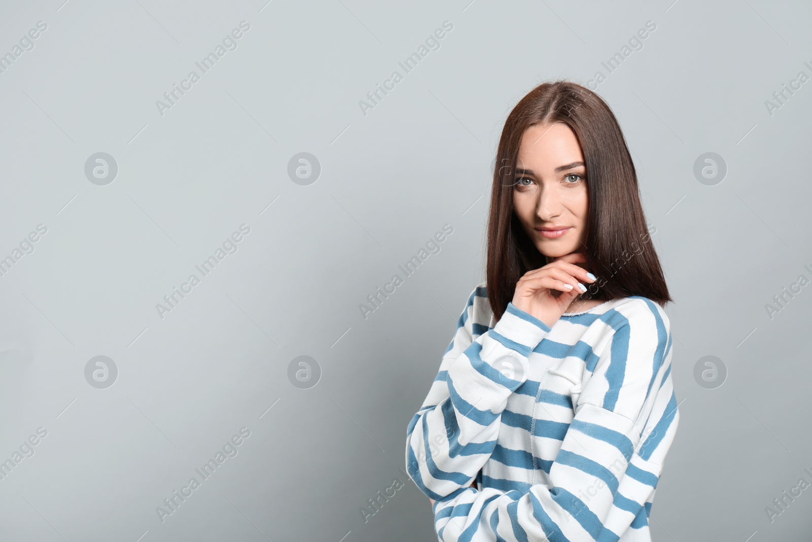 Photo of Portrait of pretty young woman with gorgeous chestnut hair on light grey background, space for text
