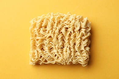 Photo of Block of quick cooking noodles on color background, top view