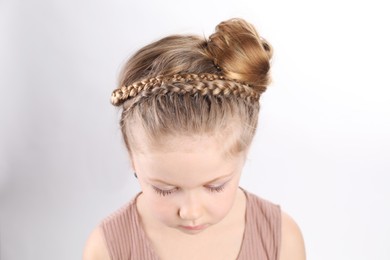 Photo of Little girl with braided hair on light grey background