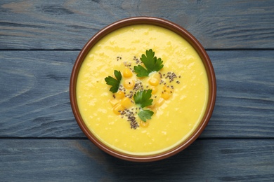 Photo of Delicious creamy corn soup on blue wooden table, top view