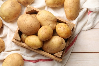 Photo of Raw fresh potatoes with crate on light wooden table, top view