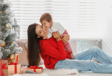 Mother and her cute baby near Christmas tree at home