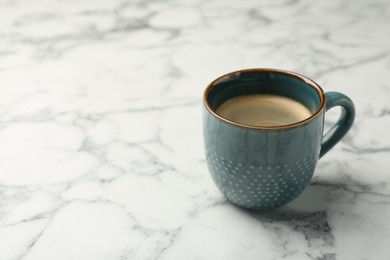 Tasty coffee in cup on white marble table. Space for text