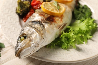 Photo of Delicious baked fish and vegetables on table, closeup