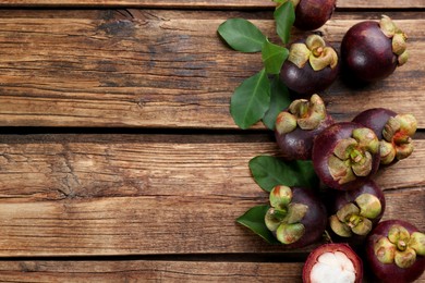 Photo of Fresh ripe mangosteen fruits on wooden table, flat lay. Space for text