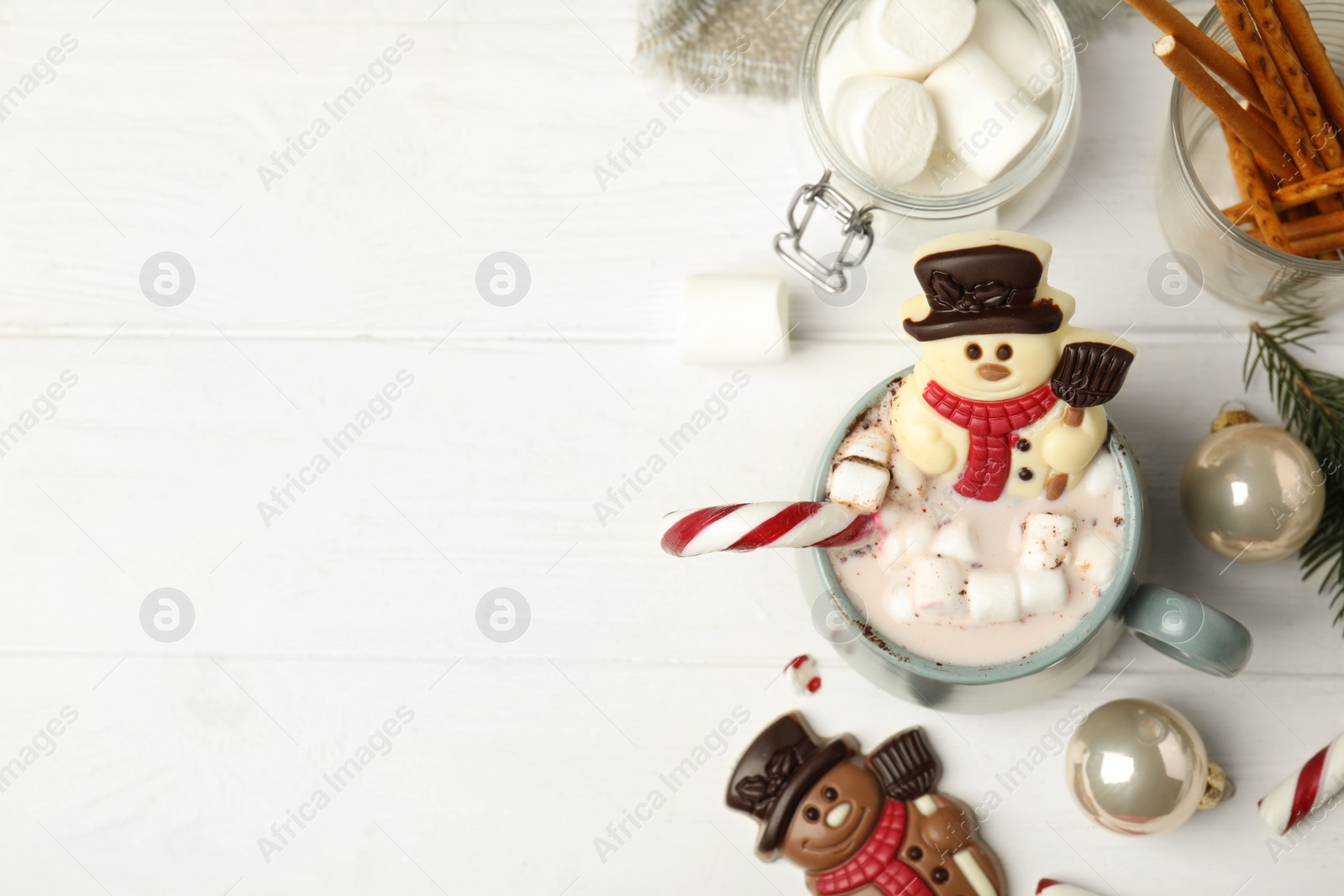 Photo of Flat lay composition with funny chocolate snowmen candies on white wooden table. Space for text