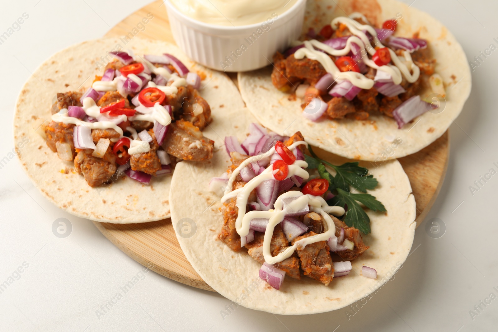 Photo of Delicious tacos with vegetables, meat and sauce on white table