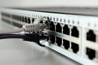 Photo of Closeup view of network switch with cables on light background. Internet connection