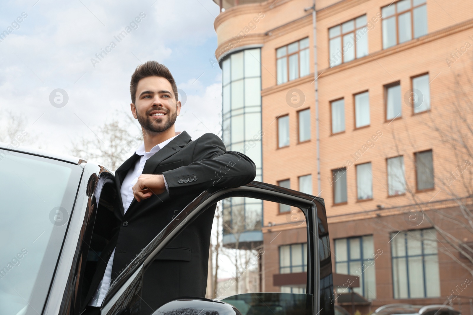 Photo of Handsome young man near modern car outdoors