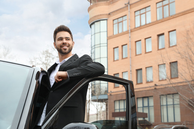 Handsome young man near modern car outdoors