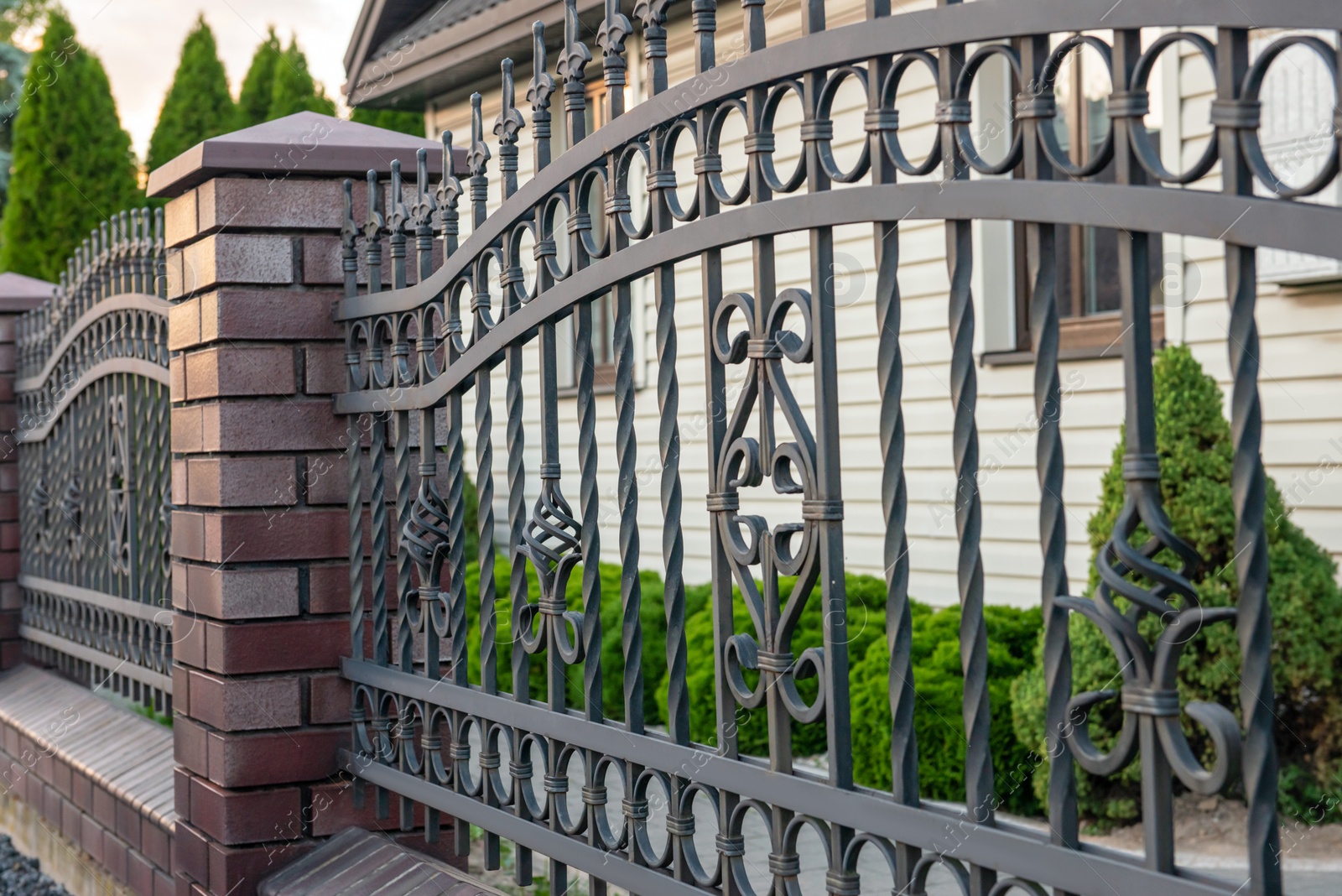 Photo of Beautiful brick fence with iron railing outdoors