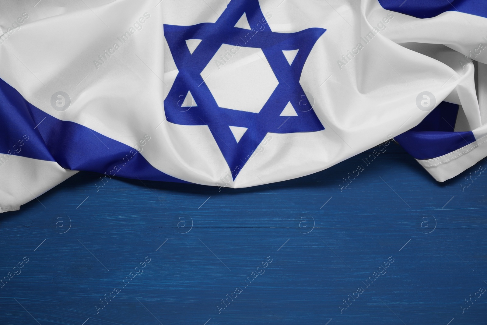 Photo of Flag of Israel on blue wooden background, space for text. National symbol