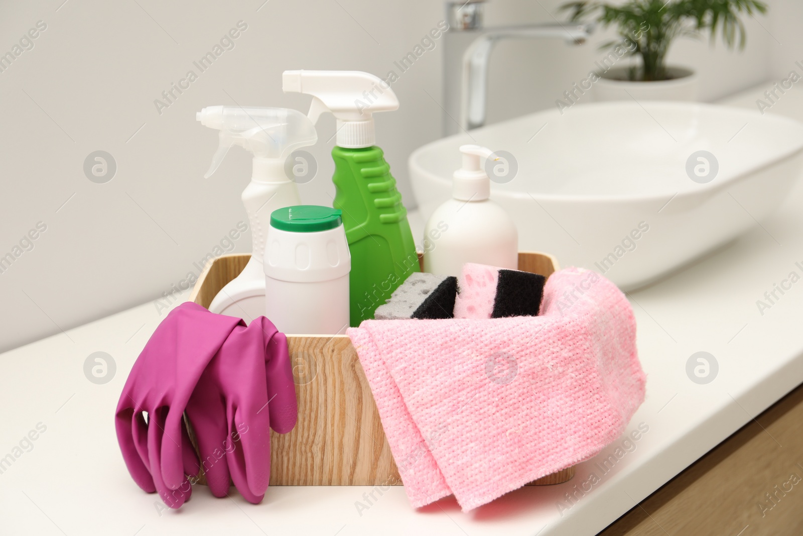 Photo of Different cleaning products in wooden box on countertop indoors