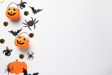 Flat lay composition with plastic pumpkin baskets, paper bats and spiders on white background, space for text. Halloween celebration