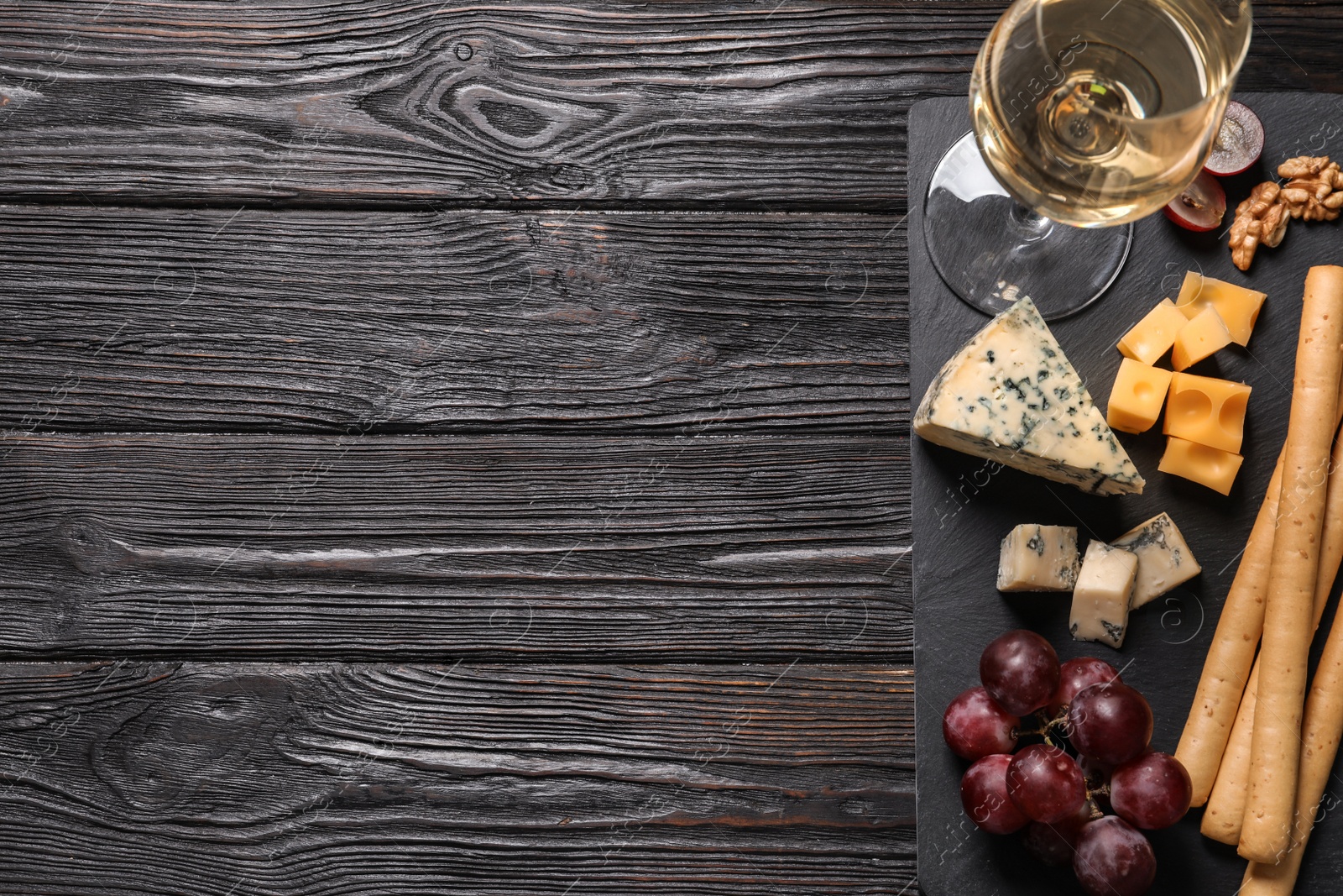 Photo of Different types of delicious cheese served on black wooden table, top view. Space for text