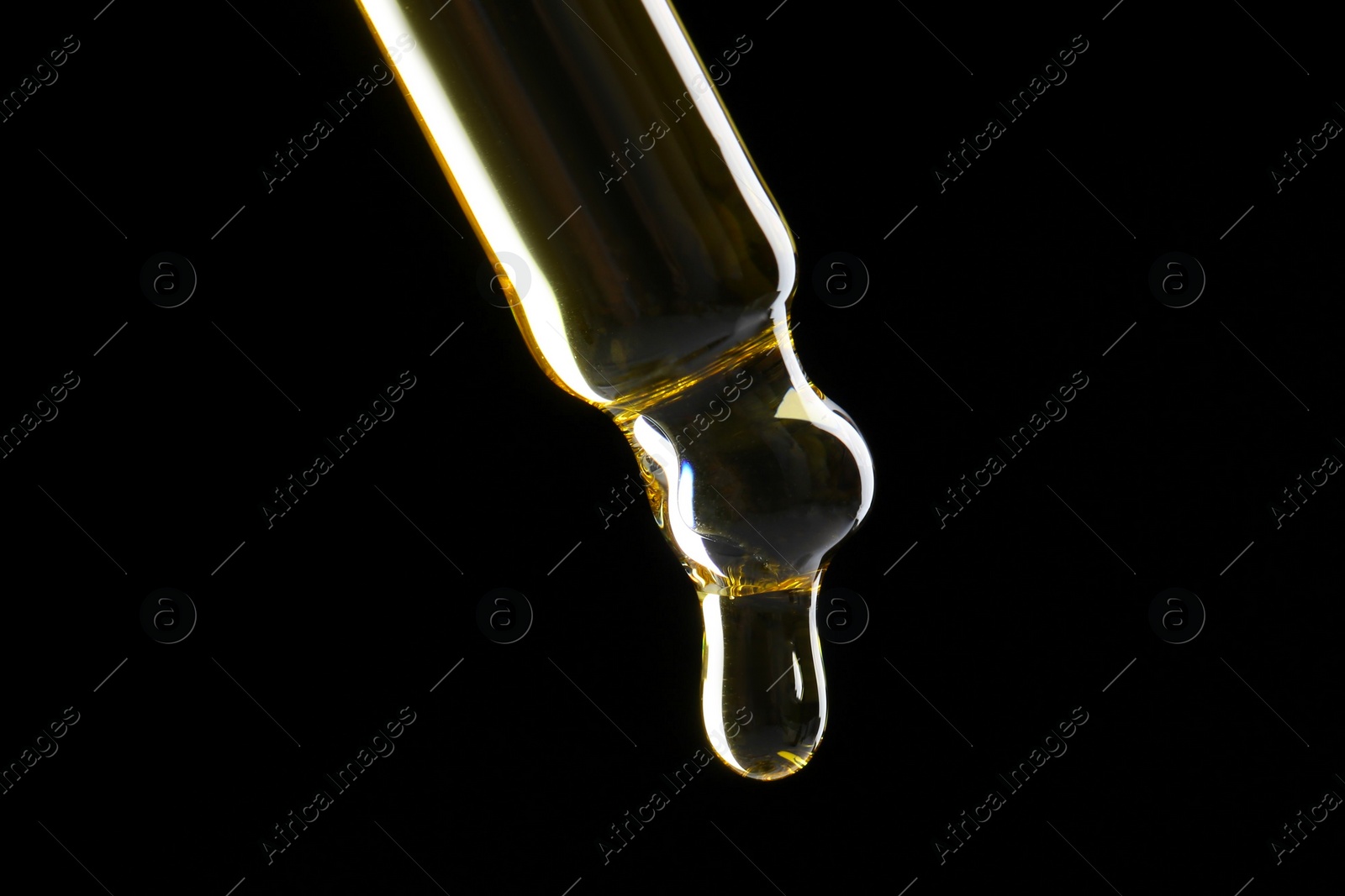 Photo of Dripping tincture from pipette on black background, closeup