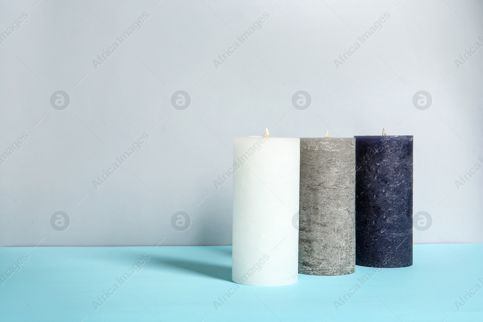 Photo of Decorative wax candles on table against light background