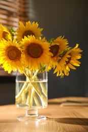 Photo of Bouquet of beautiful sunflowers on table in room