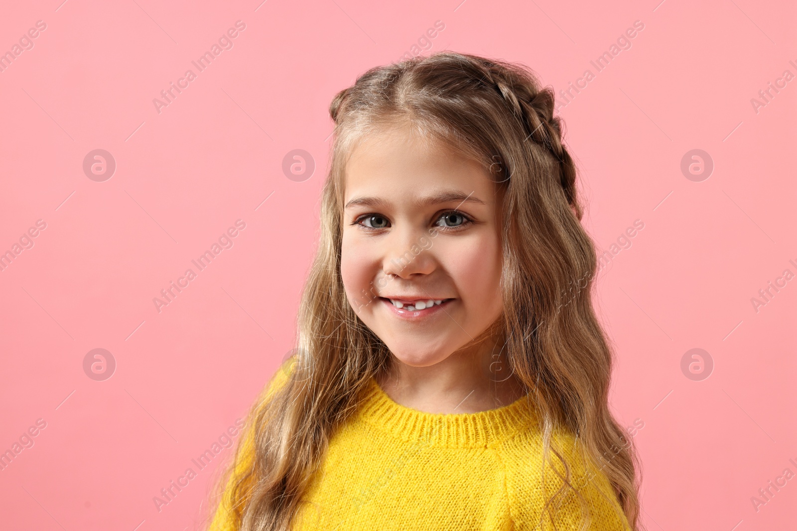 Photo of Cute little girl with braided hair on pink background