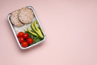 Container with rice, puffed cakes, fresh tomato, avocado and spinach on pink background, top view. Space for text