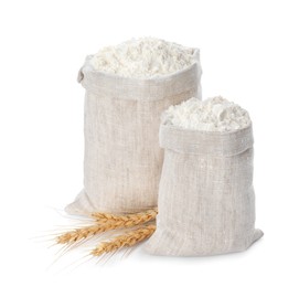 Photo of Sacks with flour and wheat spikes on white background