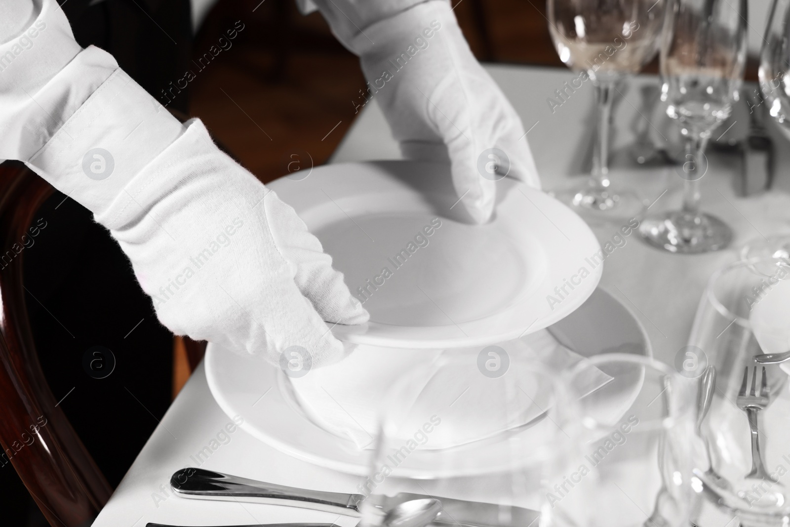 Photo of Woman setting table in restaurant, closeup. Professional butler courses