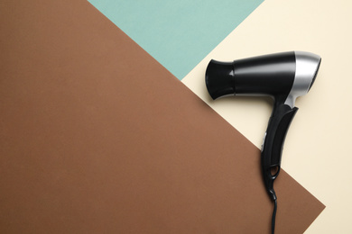 Hair dryer on color background, top view with space for text. Professional hairdresser tool