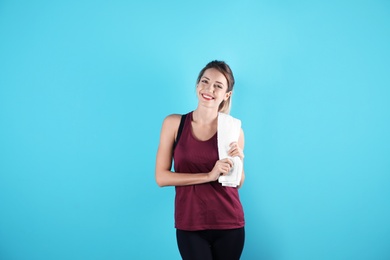 Photo of Beautiful young woman in sportswear with towel on color background