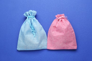 Photo of Color burlap bags on blue background, flat lay