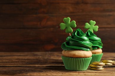 Photo of Delicious decorated cupcakes on wooden table, space for text. St. Patrick's Day celebration