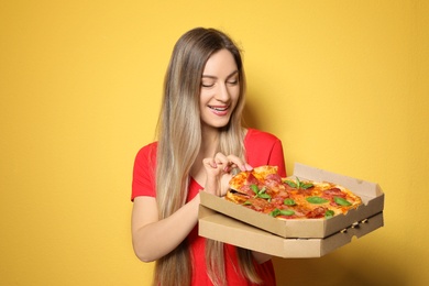 Attractive young woman with delicious pizza on color background