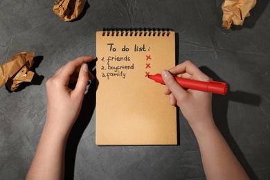 Photo of Woman checking to do list with felt pen on grey background, top view. Solitude concept