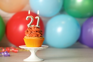 Photo of 21th birthday, coming of age party. Delicious cupcake with number shaped candles on wooden table, space for text