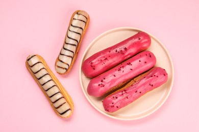 Photo of Delicious eclairs covered with glaze on pink background, flat lay