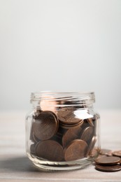 Photo of Glass jar with coins on white wooden table, closeup