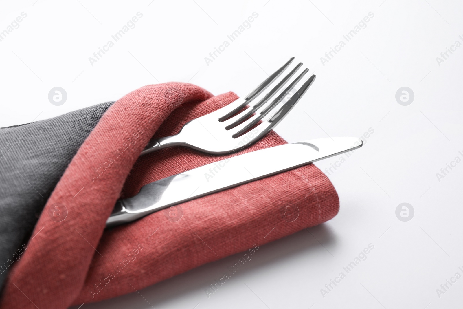 Photo of Folded napkin with fork and knife isolated on white, closeup