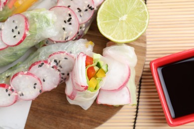 Delicious spring rolls, lime and soy sauce on table, top view