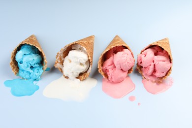 Melted ice cream in wafer cones on light blue background