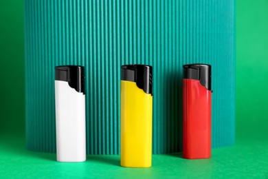 Photo of Stylish small pocket lighters and corrugated fiberboard on green background