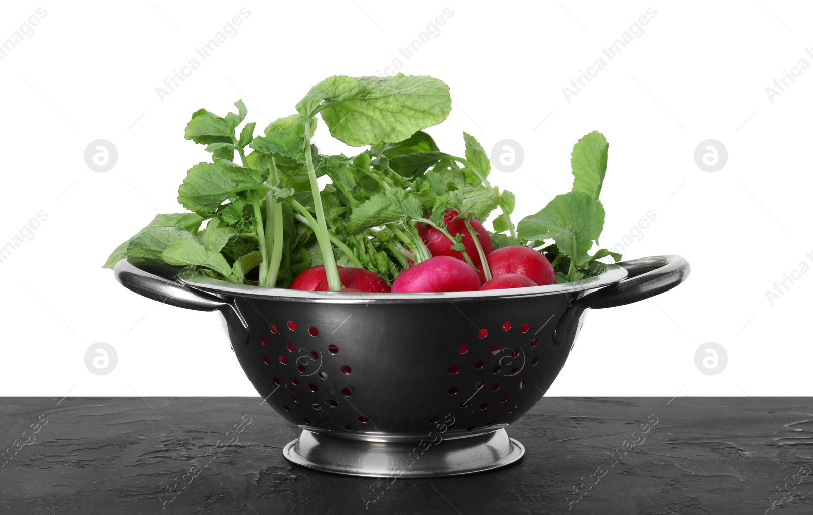 Photo of Metal colander with fresh radishes on black textured table against white background