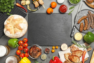 Photo of Flat lay composition with barbecued meat and vegetables on grey table. Space for text